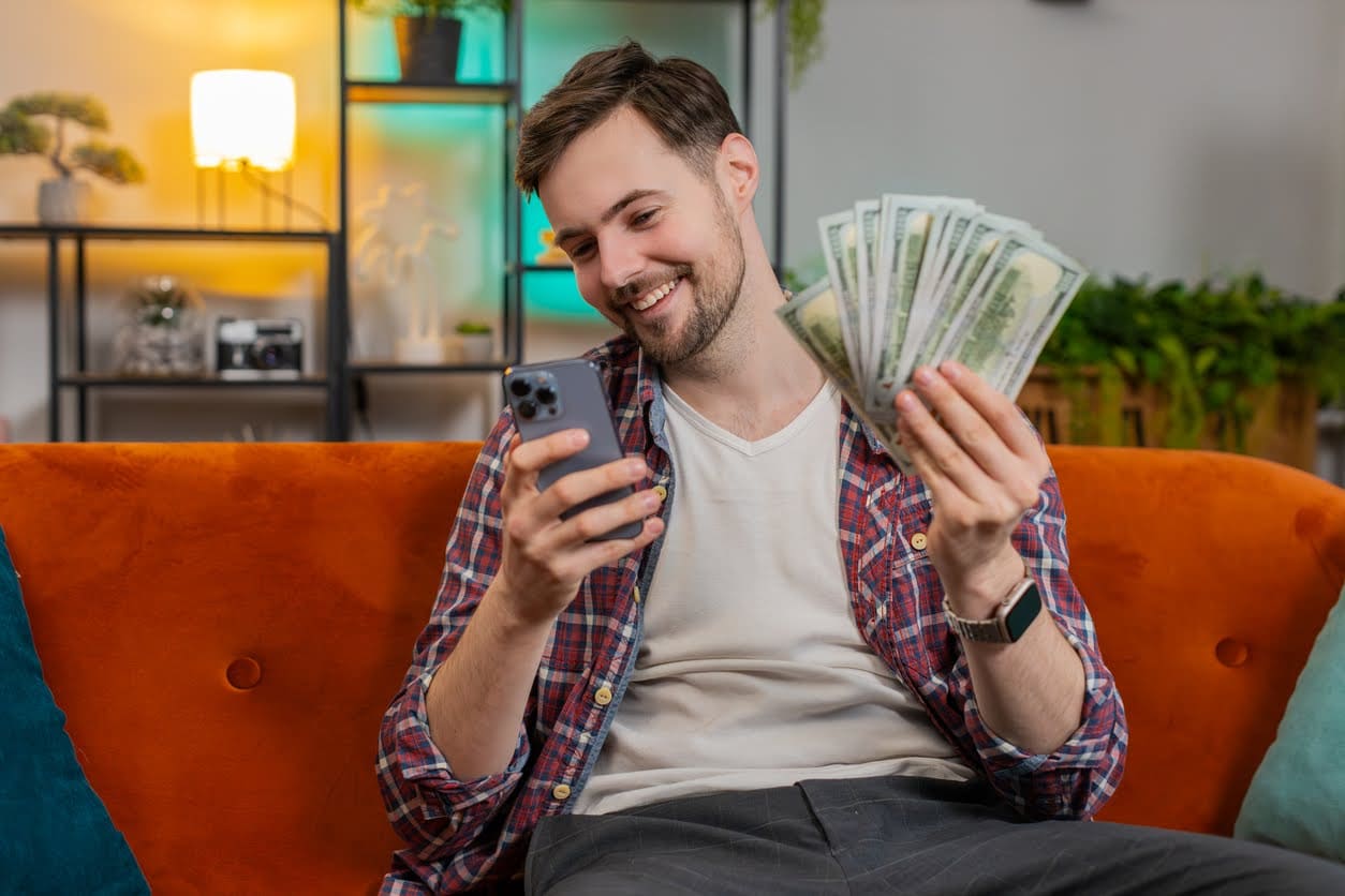 homem com celular e dinheiro na mão